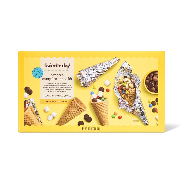 A box of Favorite Day S’mores Campfire Cones Kit with cones, mini candies and foil-wrapped cones shown on a yellow background.